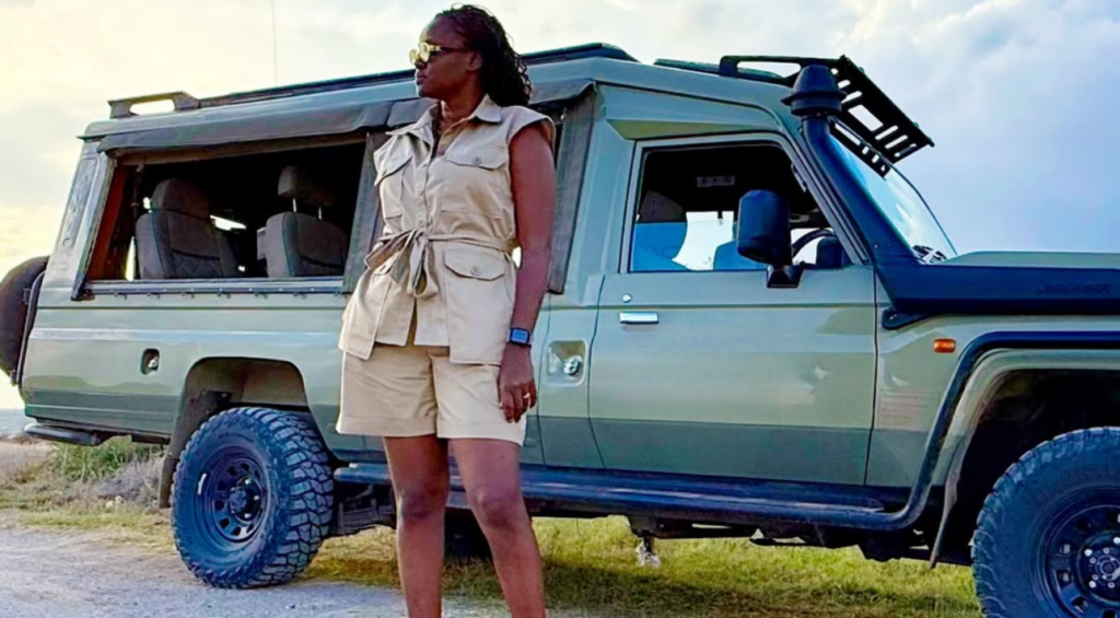 Woman in a khaki safari outfit beside a safari vehicle